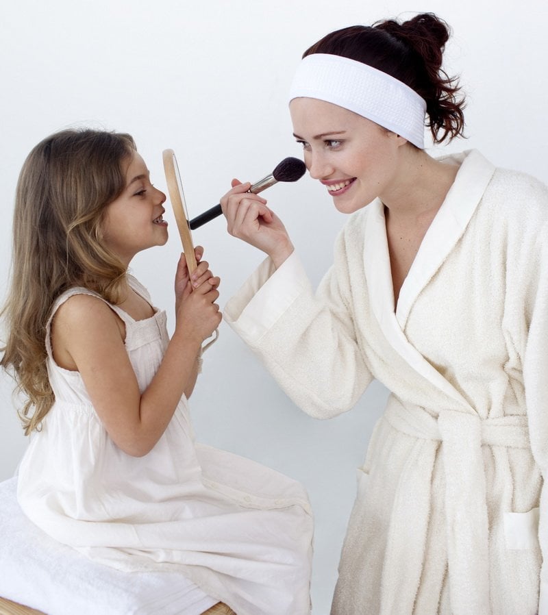 Mother applying blusher with her daughter